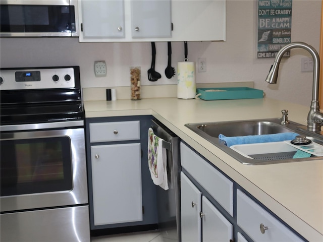 kitchen featuring light tile patterned floors, stainless steel appliances, white cabinetry, and sink