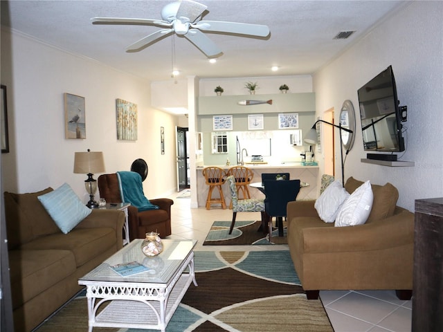 tiled living room featuring ceiling fan, sink, and a textured ceiling