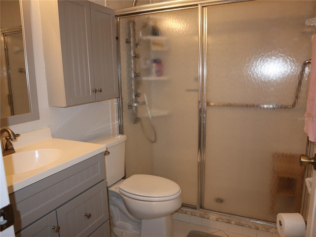 bathroom featuring tile patterned flooring, vanity, a shower with shower door, and toilet