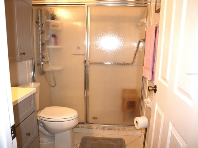 bathroom with tile patterned flooring, vanity, a shower with shower door, and toilet