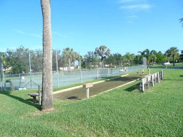 view of tennis court with a yard