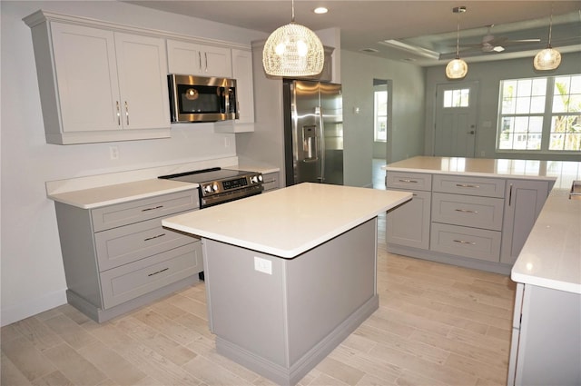 kitchen with hanging light fixtures, a kitchen island, stainless steel appliances, and light hardwood / wood-style flooring