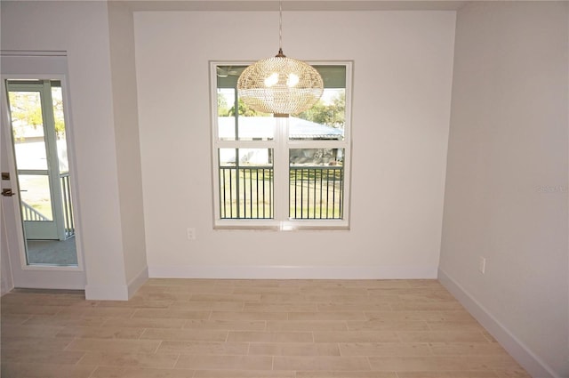 unfurnished dining area with light hardwood / wood-style floors and an inviting chandelier