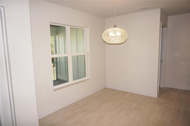 unfurnished room with a chandelier and light hardwood / wood-style floors