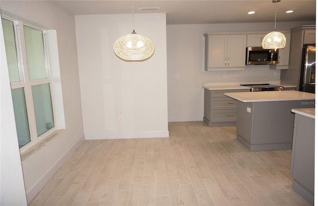 kitchen featuring gray cabinets, decorative light fixtures, a kitchen island, and stainless steel appliances