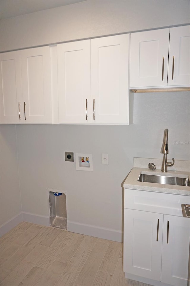 laundry room with cabinets, sink, hookup for a washing machine, hookup for an electric dryer, and light hardwood / wood-style floors