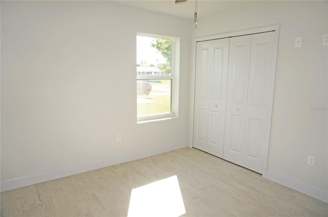 unfurnished bedroom with light wood-type flooring and a closet