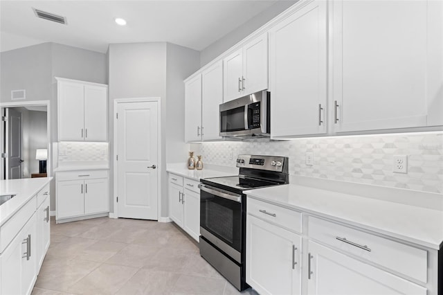 kitchen with white cabinetry, stainless steel appliances, light tile patterned flooring, and decorative backsplash