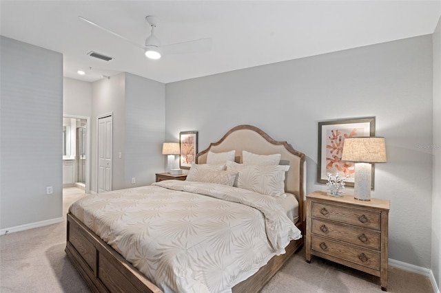 bedroom featuring ceiling fan, ensuite bathroom, light carpet, and a closet