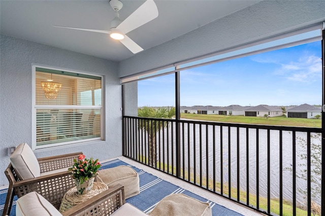 sunroom / solarium with a water view and ceiling fan with notable chandelier