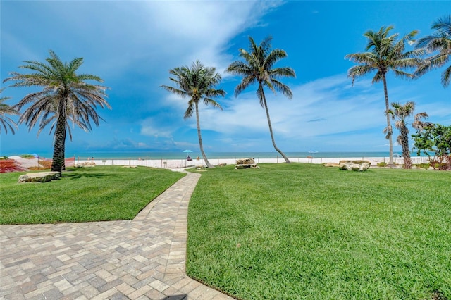 view of property's community with a water view, a beach view, and a yard