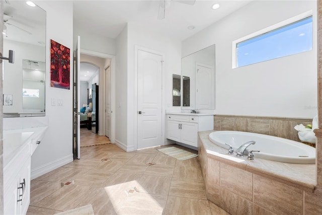 bathroom with tiled tub, ceiling fan, tile patterned flooring, and vanity