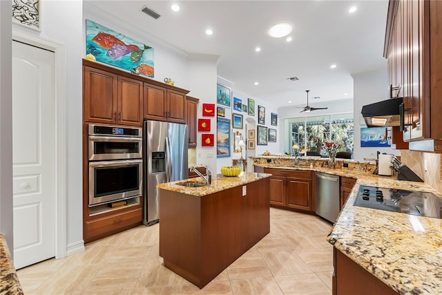 kitchen featuring light stone countertops, stainless steel appliances, premium range hood, a center island with sink, and ornamental molding