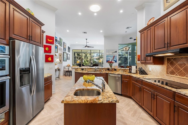 kitchen featuring a center island with sink, sink, ceiling fan, ornamental molding, and appliances with stainless steel finishes