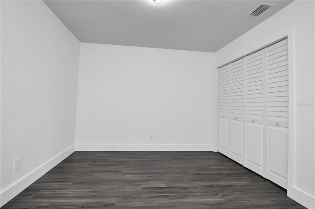 unfurnished bedroom featuring a closet and dark wood-type flooring