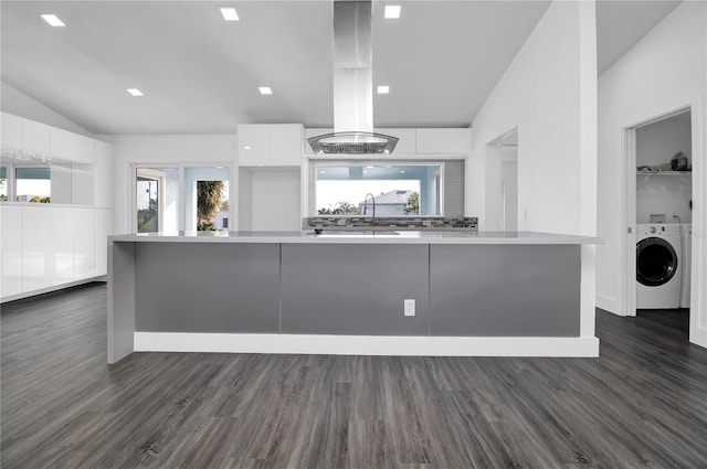 kitchen with washer / clothes dryer, white cabinets, dark hardwood / wood-style floors, and vaulted ceiling