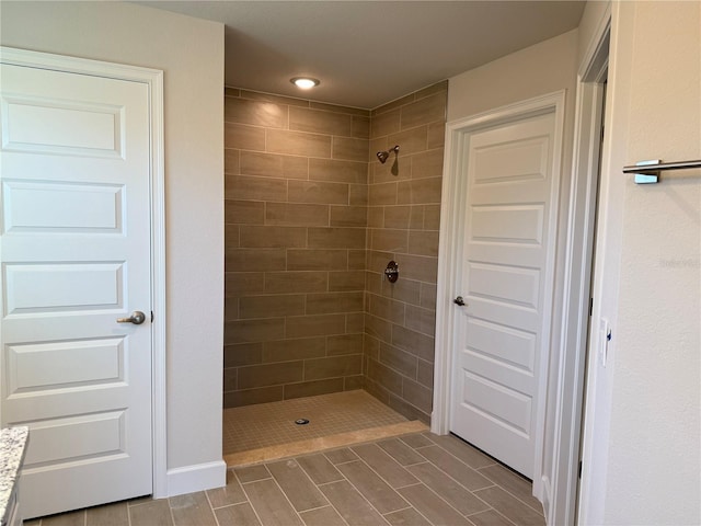 full bath featuring a tile shower and wood finish floors