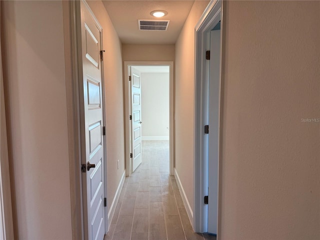 hallway featuring visible vents and baseboards