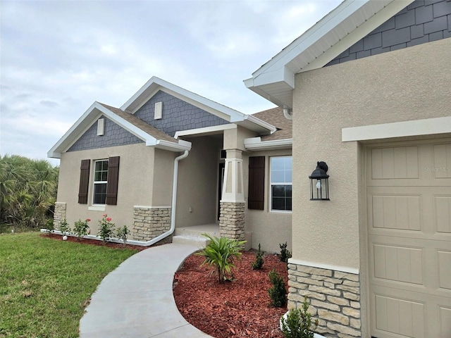 view of exterior entry with stone siding, a shingled roof, a lawn, and stucco siding