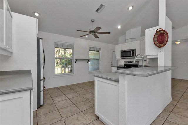 kitchen featuring kitchen peninsula, stainless steel appliances, vaulted ceiling, ceiling fan, and white cabinets