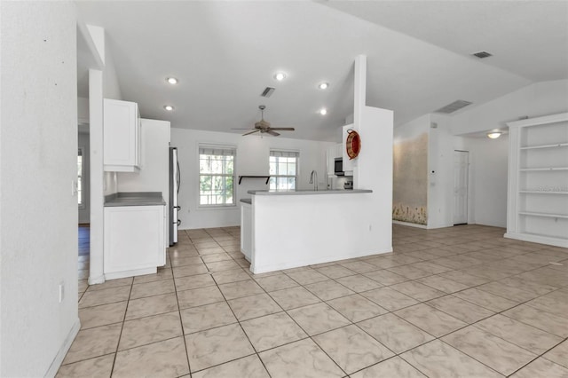 kitchen featuring kitchen peninsula, stainless steel appliances, vaulted ceiling, ceiling fan, and white cabinetry