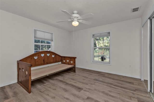 bedroom with light hardwood / wood-style flooring, multiple windows, and ceiling fan