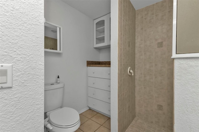 bathroom featuring tiled shower, tile patterned flooring, and toilet