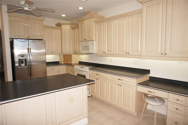 kitchen featuring cream cabinetry, light tile patterned floors, white appliances, and ceiling fan