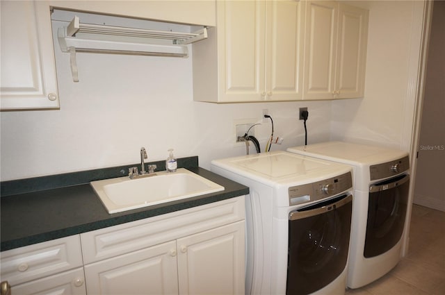 laundry room with washing machine and clothes dryer, sink, light tile patterned floors, and cabinets