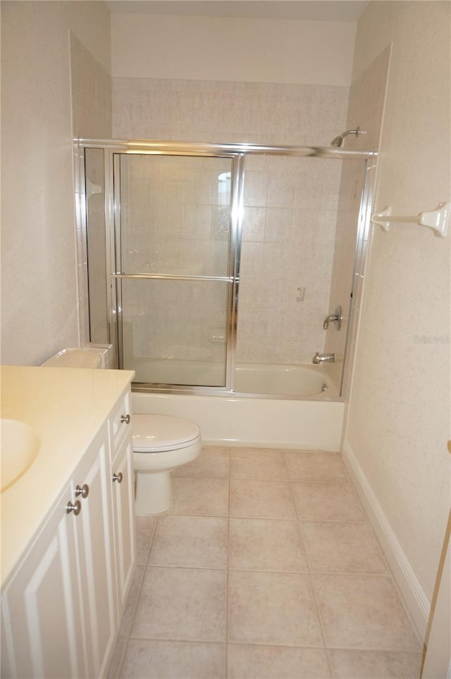 full bathroom featuring tile patterned floors, vanity, toilet, and bath / shower combo with glass door