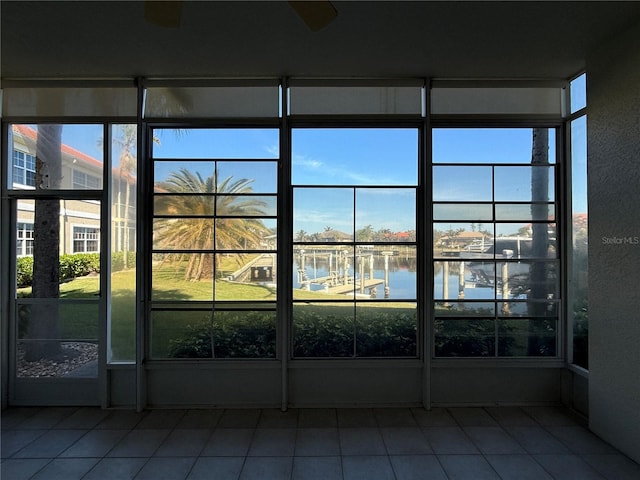 unfurnished sunroom featuring ceiling fan and a water view