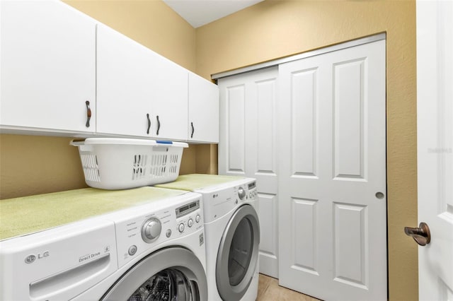 laundry area featuring washer and clothes dryer, cabinets, and light tile patterned floors