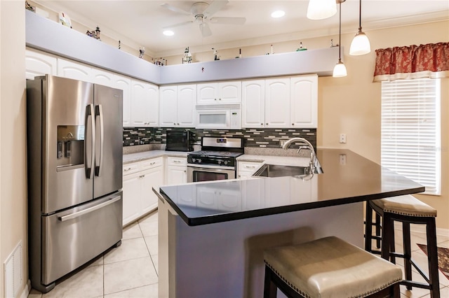 kitchen with kitchen peninsula, appliances with stainless steel finishes, a kitchen bar, sink, and white cabinets