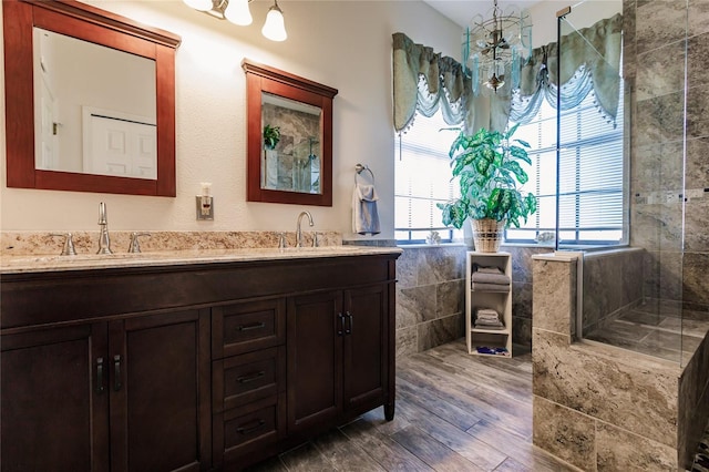 bathroom with hardwood / wood-style flooring, vanity, and tiled shower