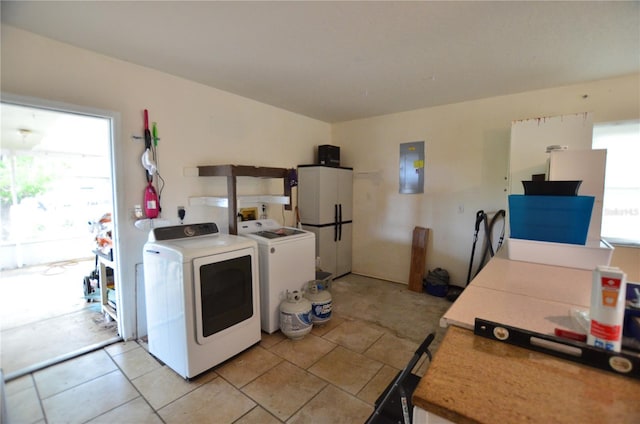 laundry room featuring plenty of natural light, washer and dryer, light tile patterned flooring, and electric panel