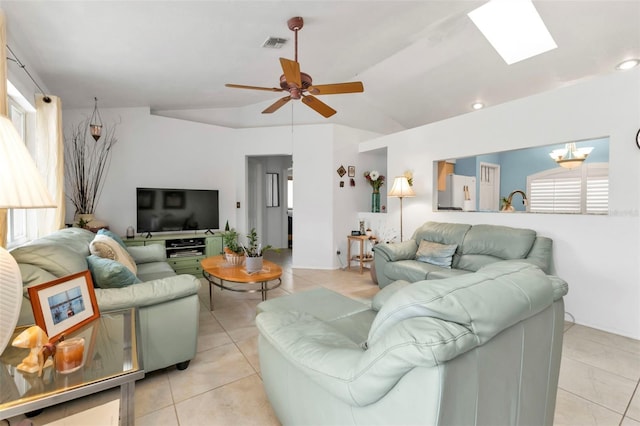 tiled living room featuring ceiling fan with notable chandelier and lofted ceiling with skylight