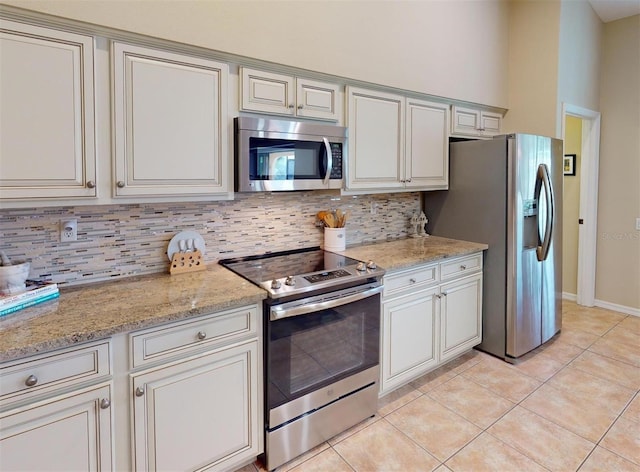 kitchen featuring decorative backsplash, stainless steel appliances, light stone countertops, and light tile patterned flooring