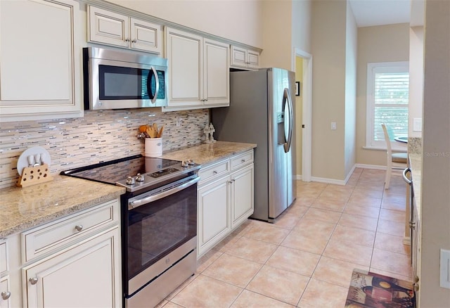 kitchen featuring light stone countertops, decorative backsplash, light tile patterned floors, and stainless steel appliances