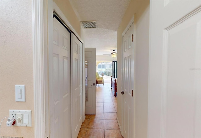 hallway featuring a textured ceiling and light tile patterned flooring