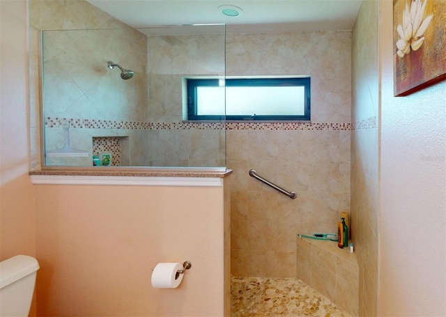 bathroom featuring toilet and tiled shower