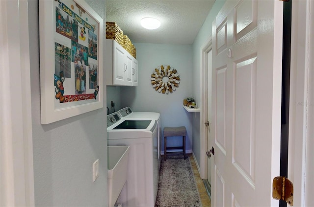 laundry area featuring tile patterned flooring, cabinets, a textured ceiling, and washing machine and clothes dryer