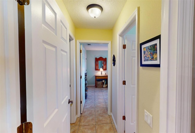 hallway with light tile patterned flooring and a textured ceiling