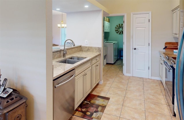 kitchen with sink, separate washer and dryer, light stone counters, decorative light fixtures, and appliances with stainless steel finishes