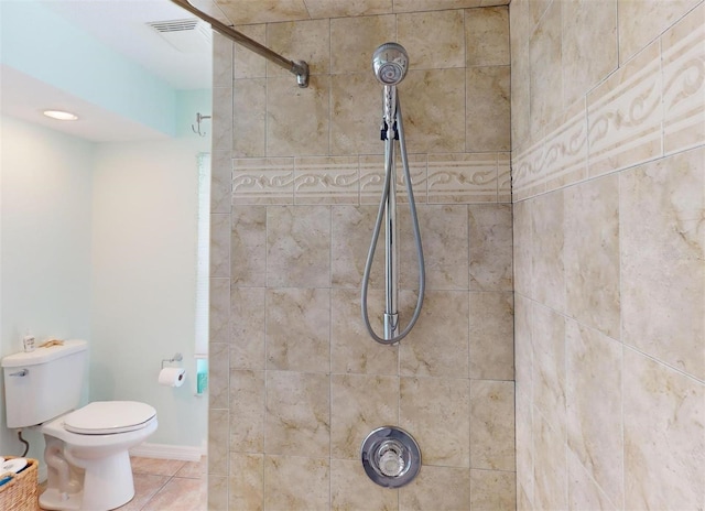 bathroom with tile patterned flooring, toilet, and tiled shower