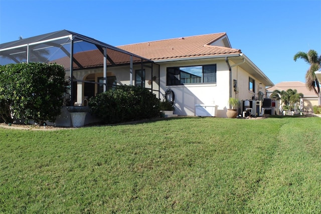 rear view of property featuring a lanai and a lawn