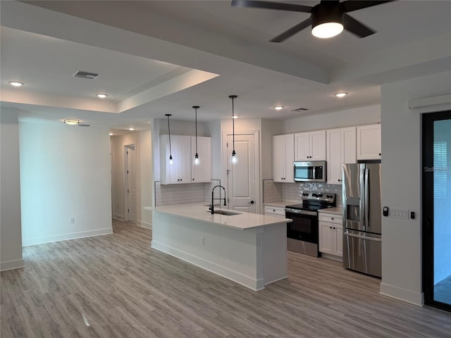 kitchen with white cabinets, light wood-type flooring, kitchen peninsula, and appliances with stainless steel finishes