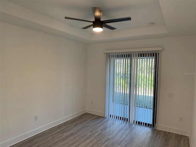 unfurnished room with a tray ceiling, ceiling fan, and hardwood / wood-style flooring