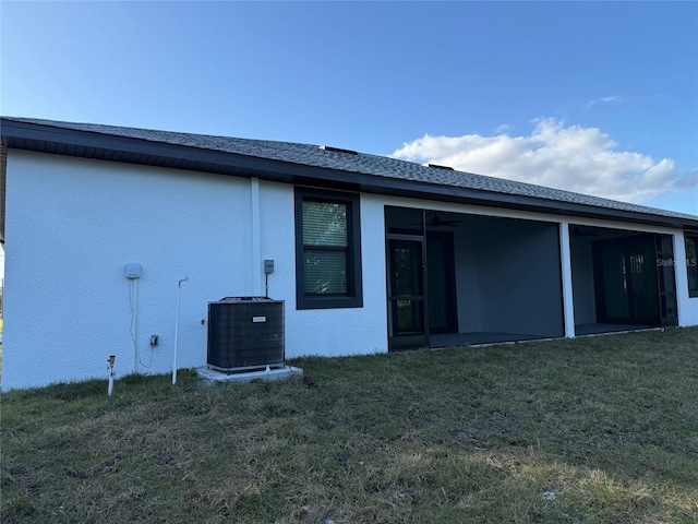 back of house featuring a lawn, a sunroom, and cooling unit