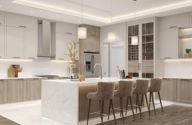 kitchen with appliances with stainless steel finishes, a kitchen island with sink, dark wood-type flooring, and wall chimney range hood