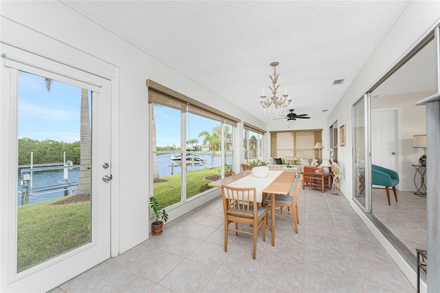 sunroom with ceiling fan with notable chandelier and a water view